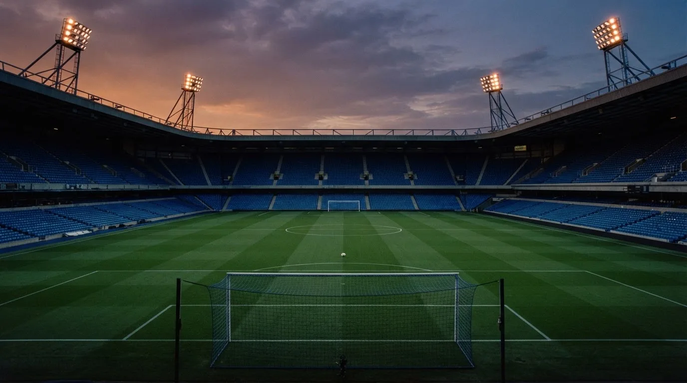 An empty football stadium with floodlight masts at dusk