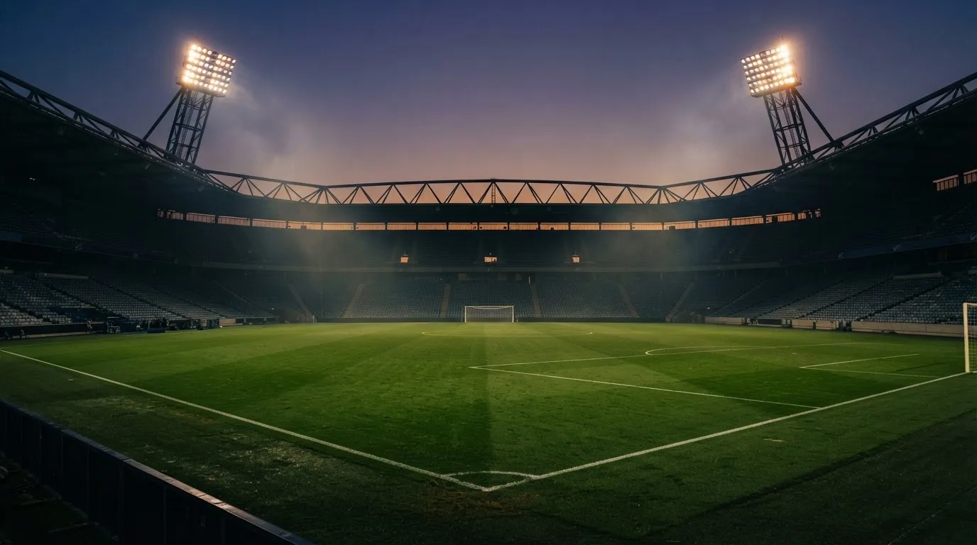 An empty football stadium with floodlight masts at dusk