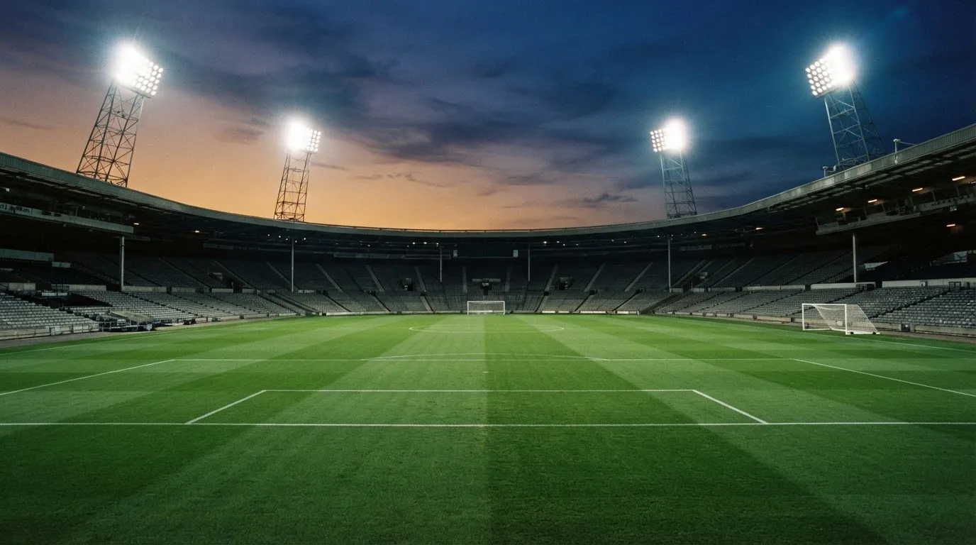 An empty football stadium with floodlight masts at dusk