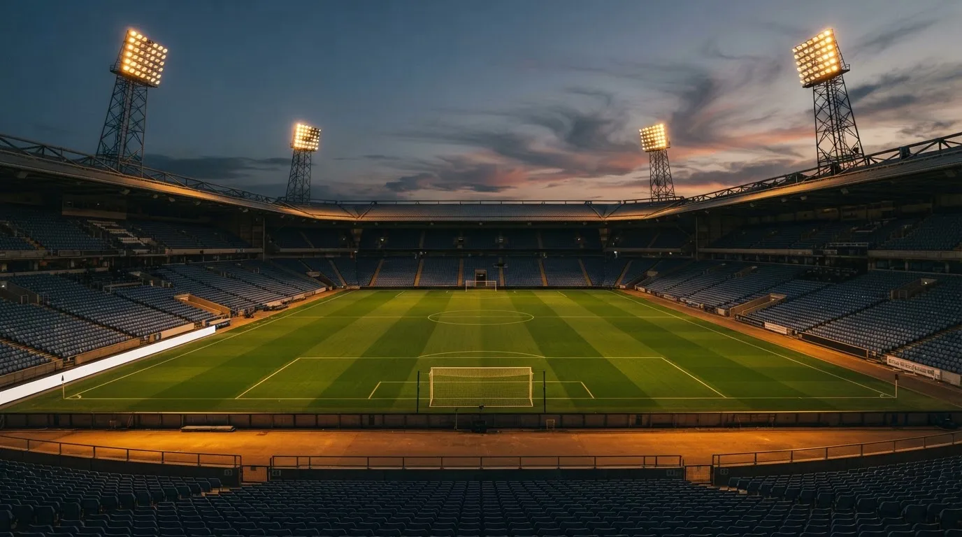 An empty football stadium with floodlight masts at dusk