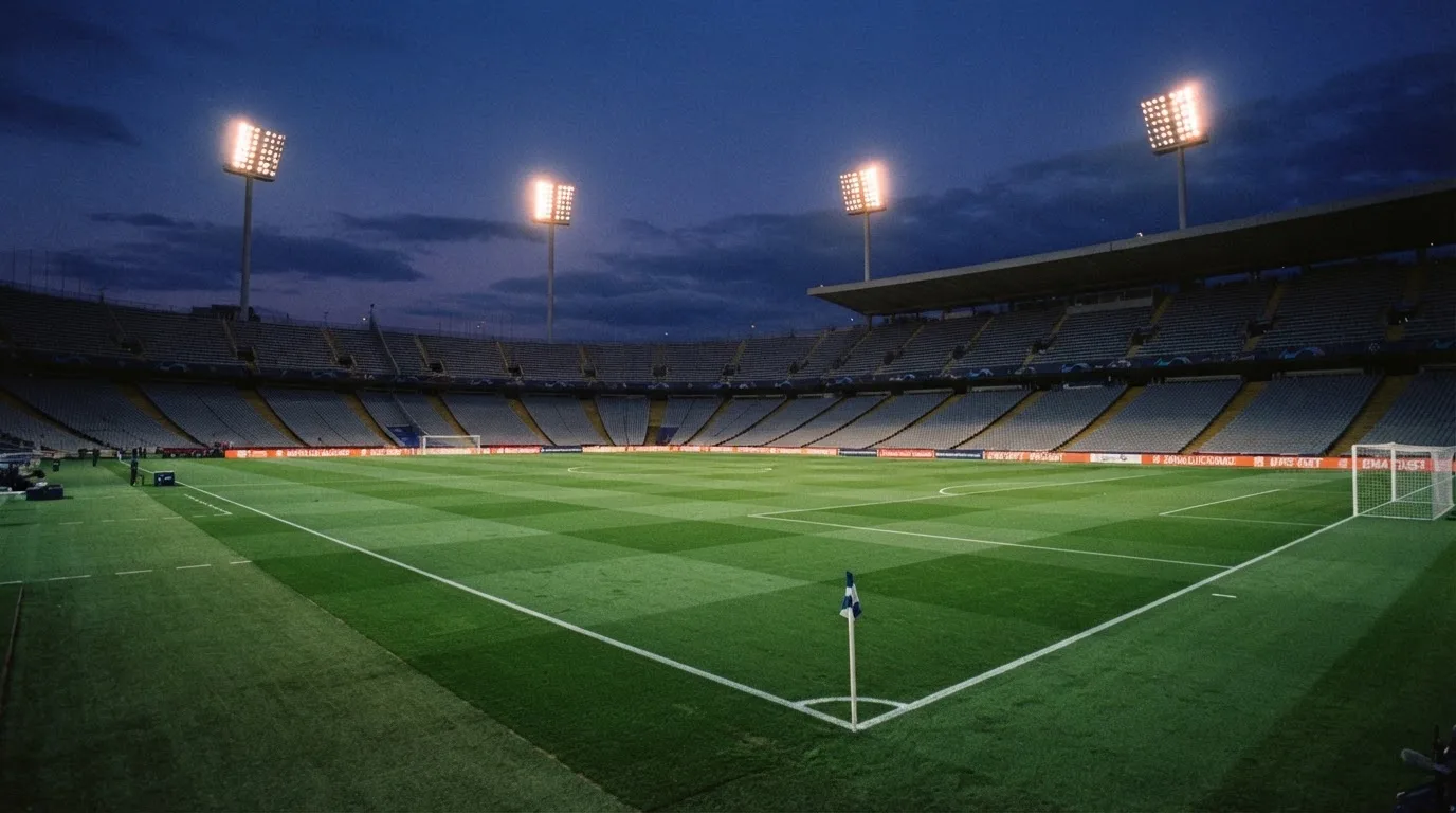 An empty football stadium with floodlight masts at dusk