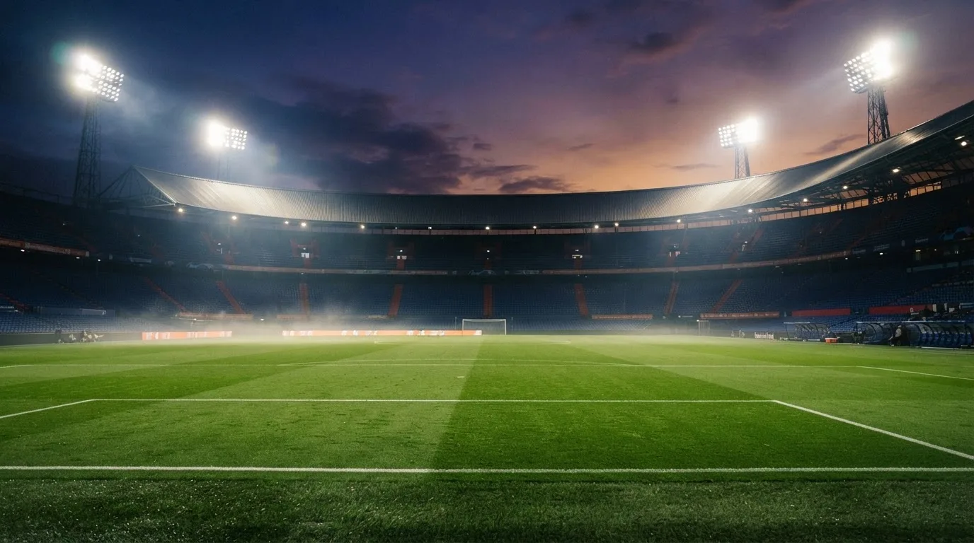 An empty football stadium with floodlight masts at dusk