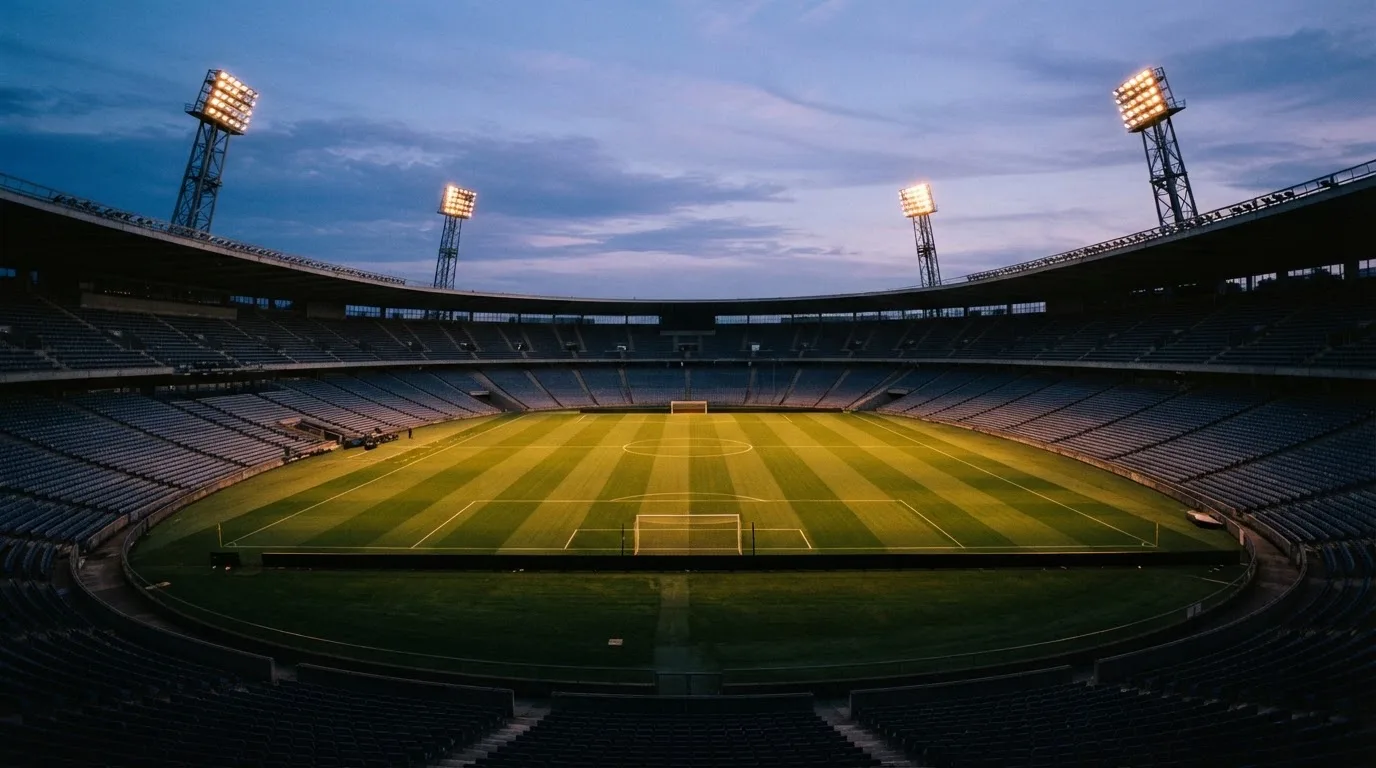 An empty football stadium with floodlight masts at dusk