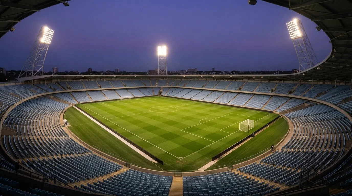 An empty football stadium with floodlight masts at dusk