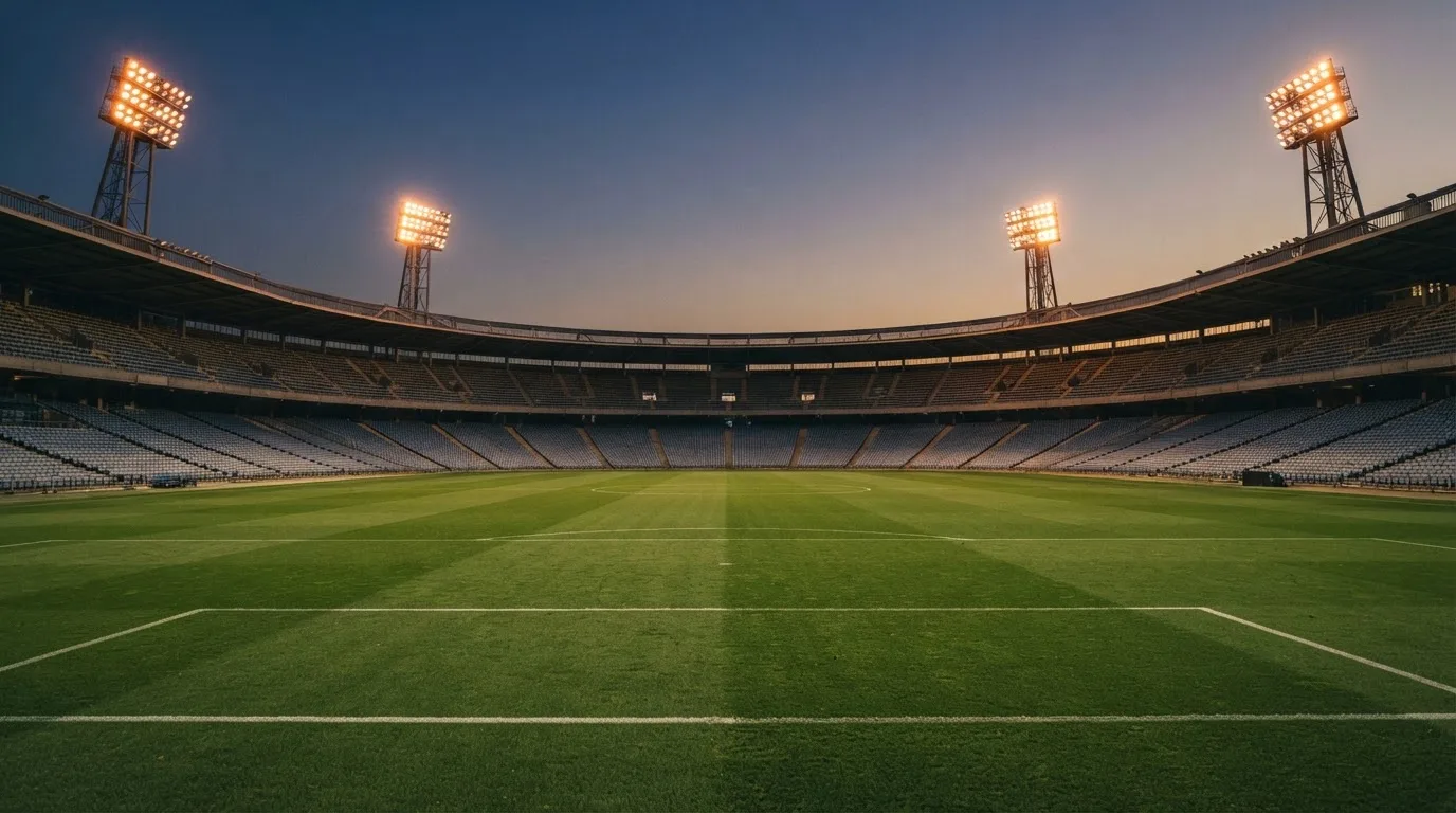 An empty football stadium with floodlight masts at dusk