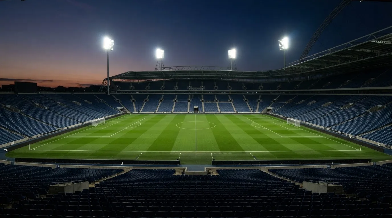 An empty football stadium with floodlight masts at dusk