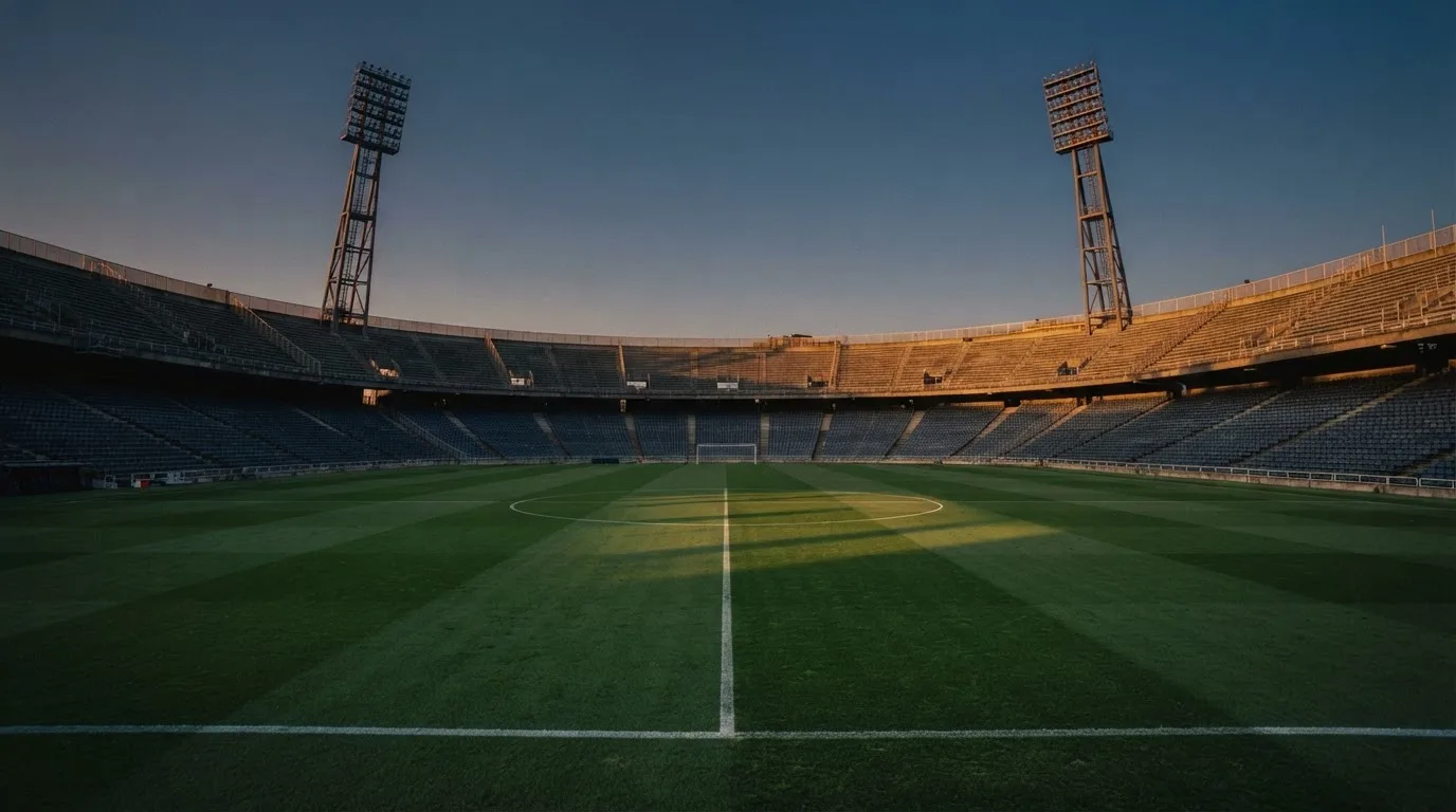 An empty football stadium with floodlight masts at dusk