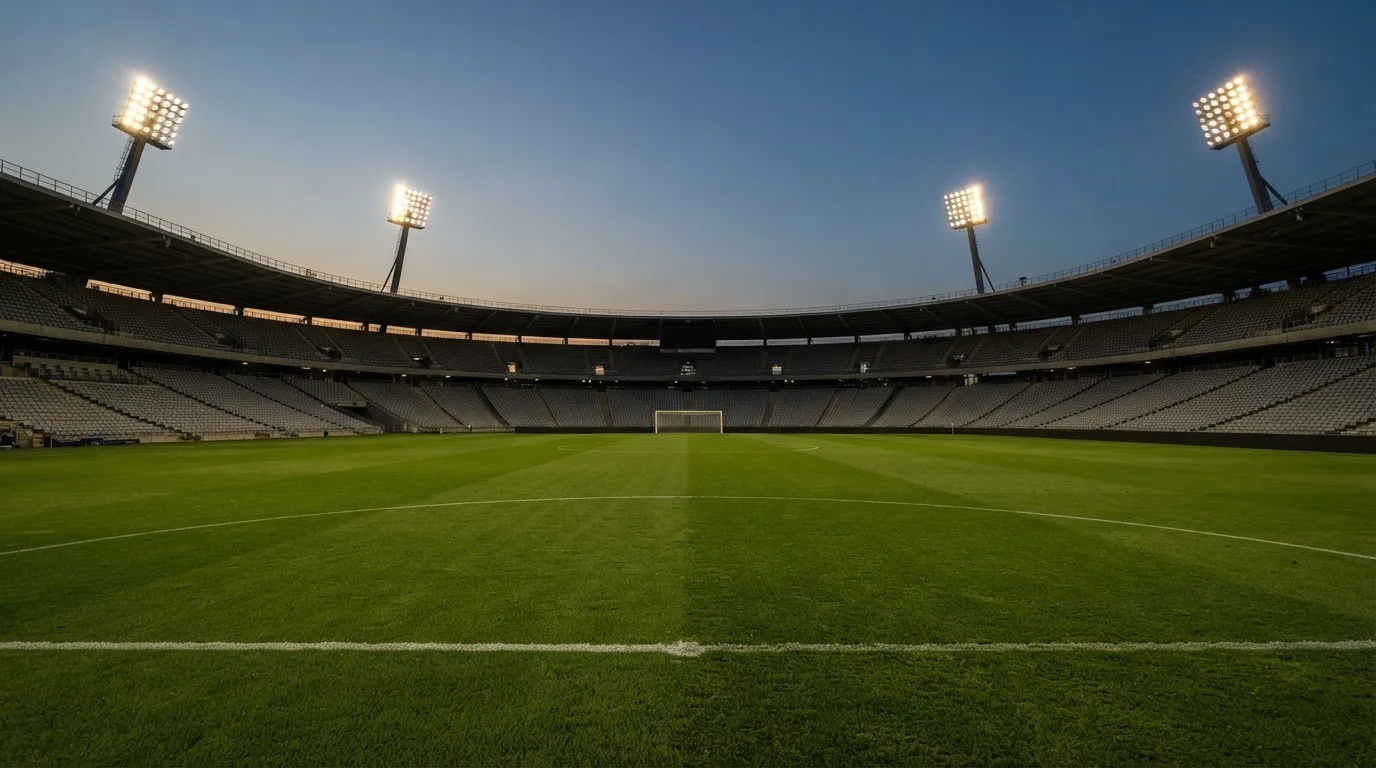 An empty football stadium with floodlight masts at dusk
