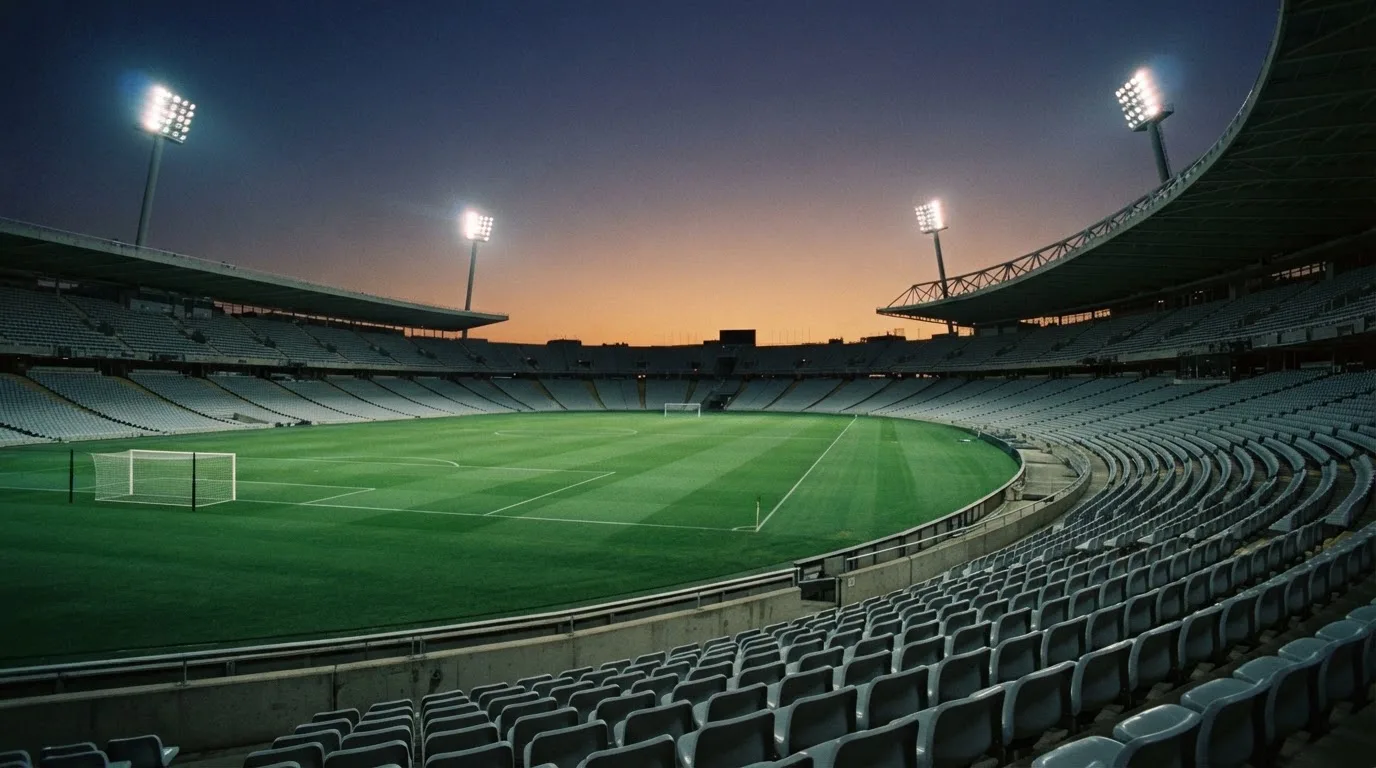 An empty football stadium with floodlight masts at dusk