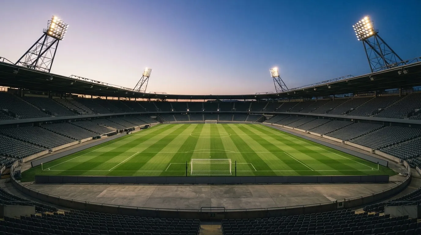 An empty football stadium with floodlight masts at dusk