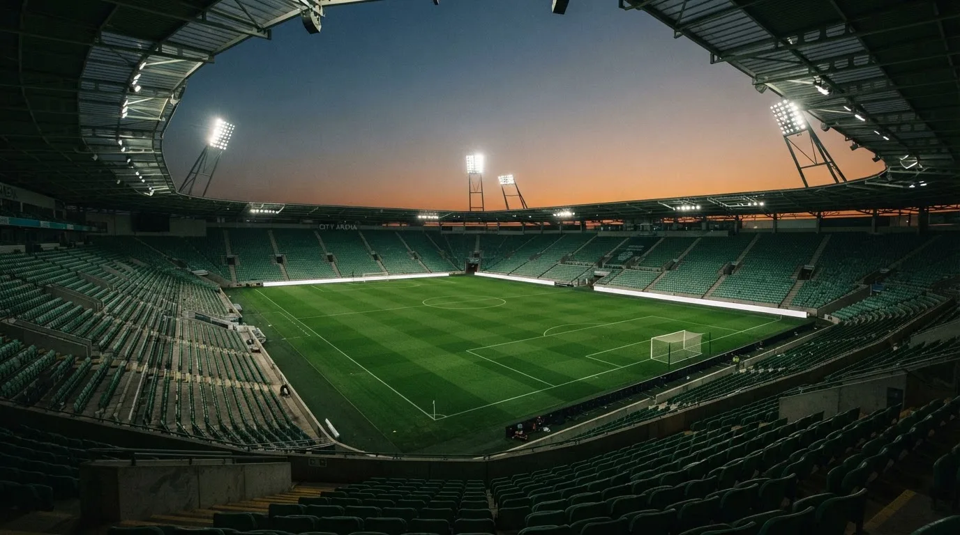 An empty football stadium with floodlight masts at dusk