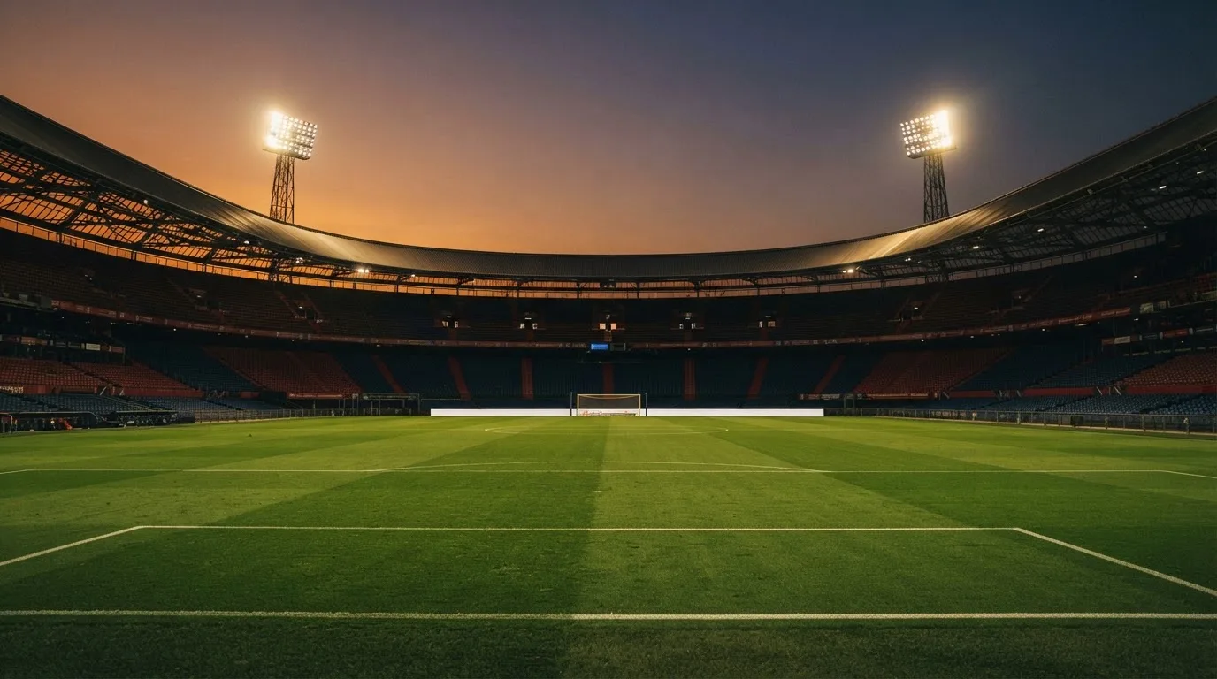 An empty football stadium with floodlight masts at dusk