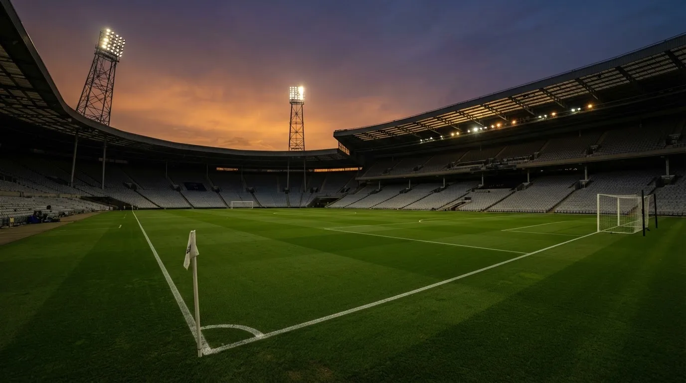 An empty football stadium with floodlight masts at dusk