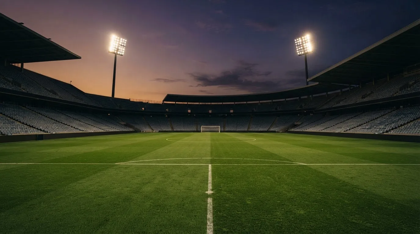 An empty football stadium with floodlight masts at dusk