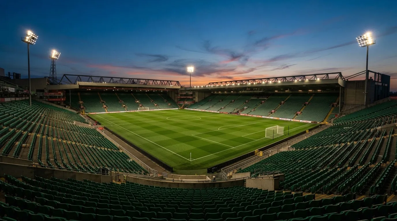 An empty football stadium with floodlight masts at dusk