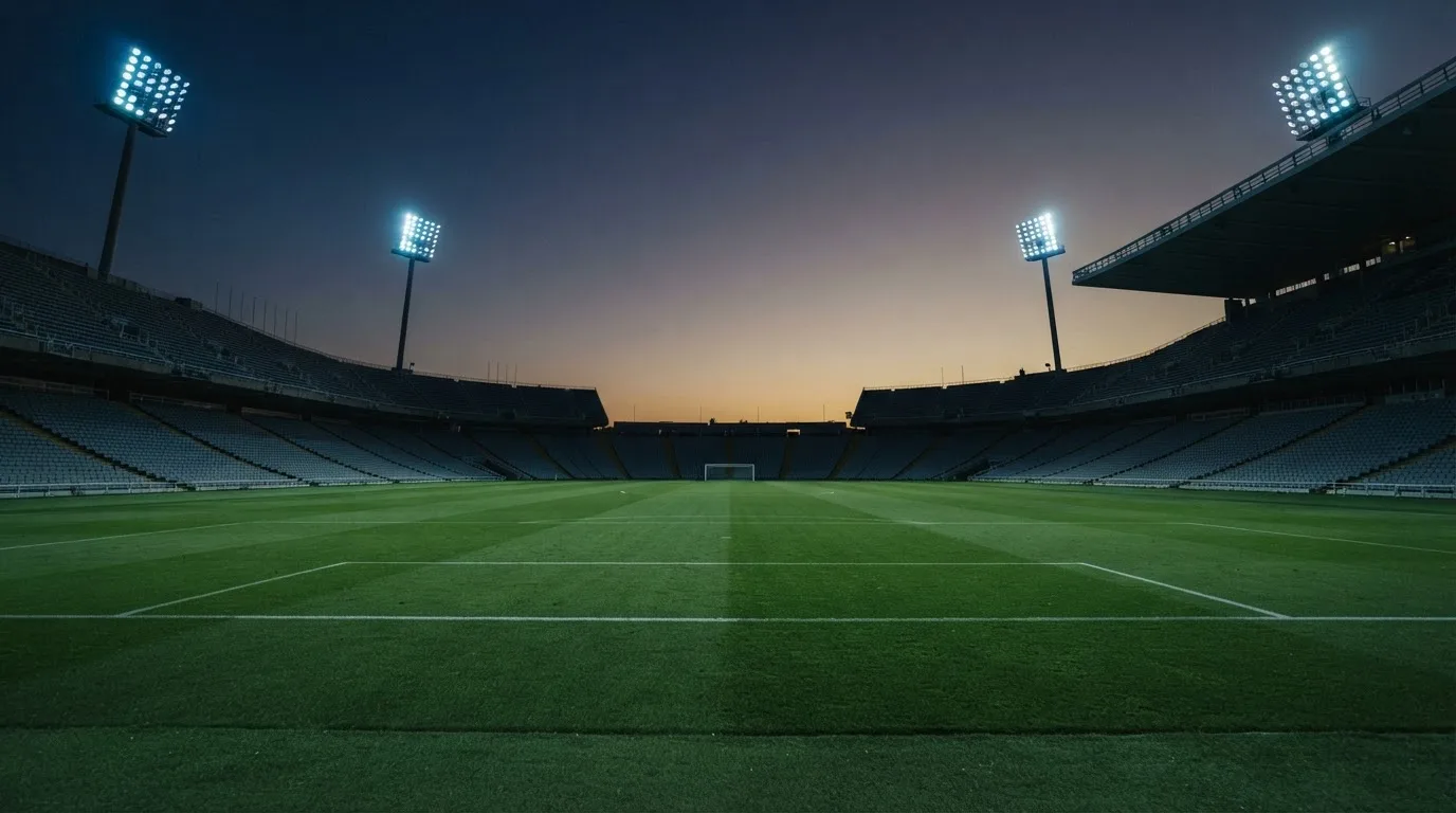 An empty football stadium with floodlight masts at dusk