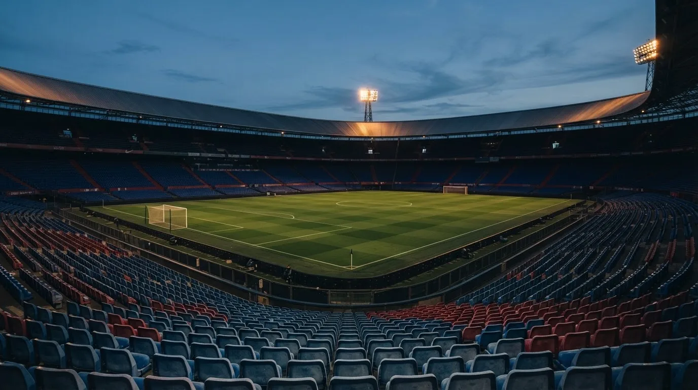 An empty football stadium with floodlight masts at dusk
