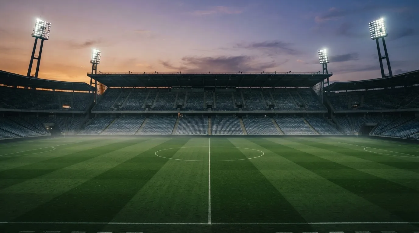 An empty football stadium with floodlight masts at dusk