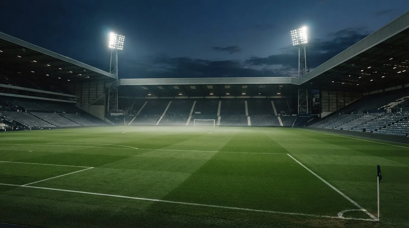 An empty football stadium with floodlight masts at dusk