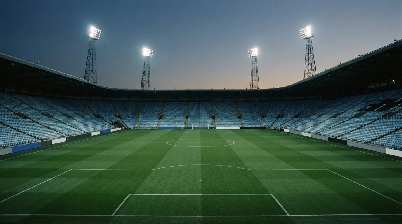 An empty football stadium with floodlight masts at dusk
