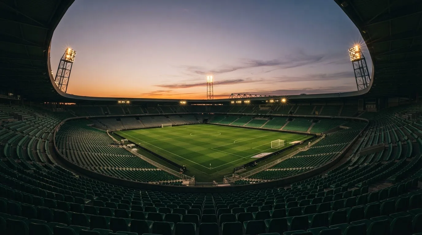 An empty football stadium with floodlight masts at dusk