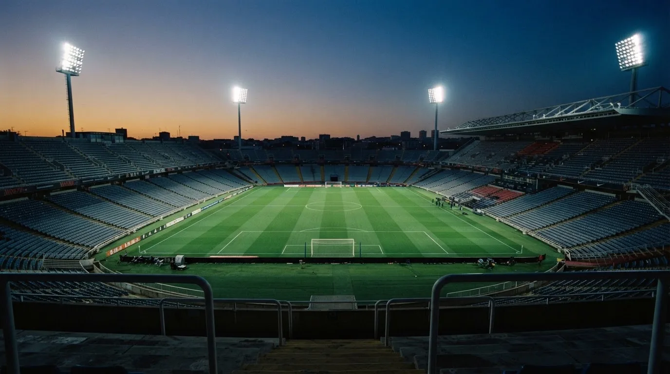 An empty football stadium with floodlight masts at dusk