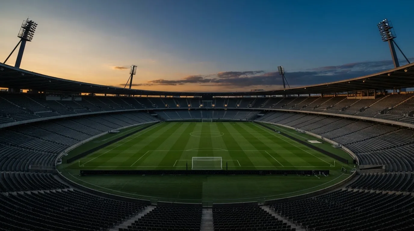 An empty football stadium with floodlight masts at dusk