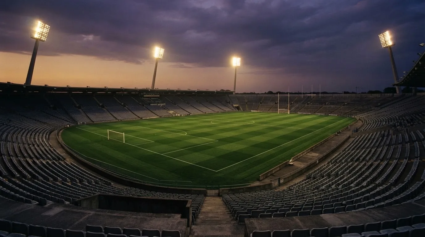 An empty football stadium with floodlight masts at dusk