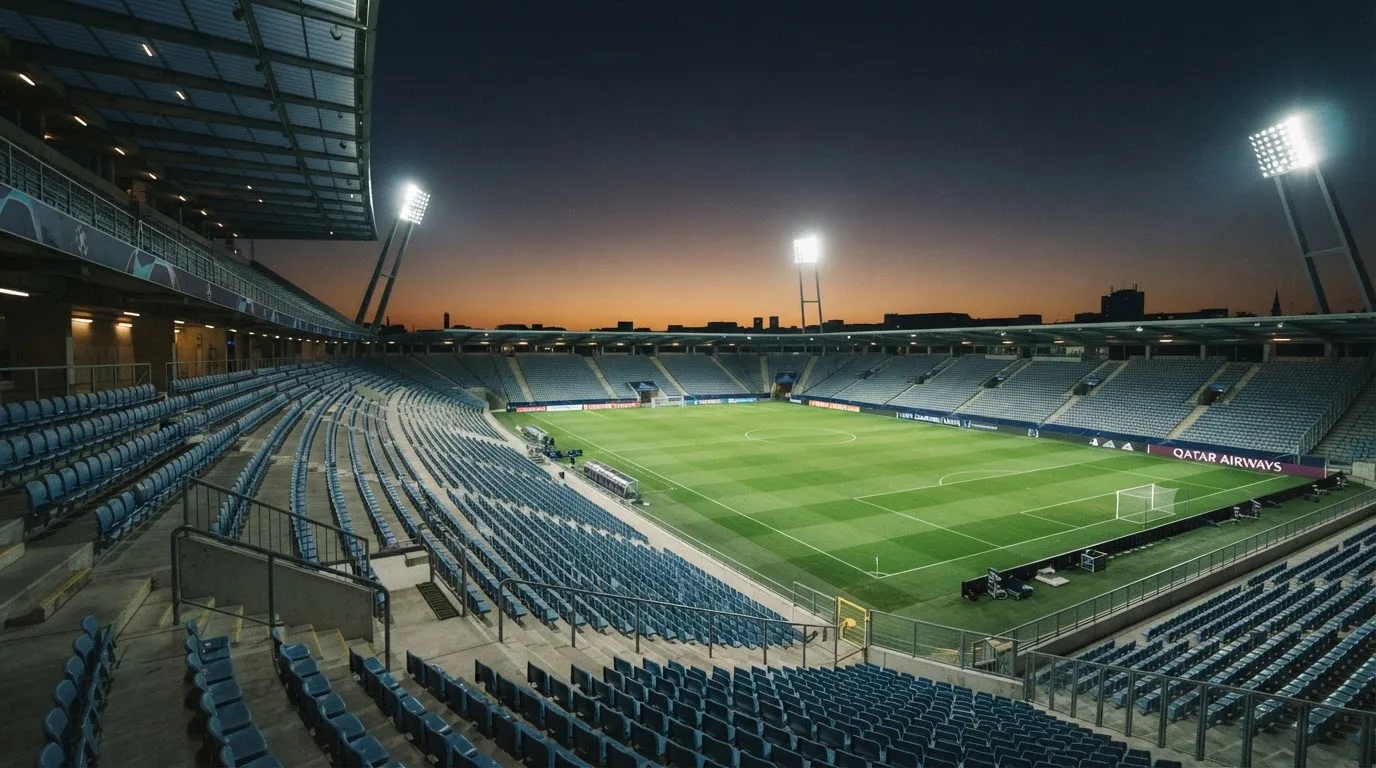 An empty football stadium with floodlight masts at dusk