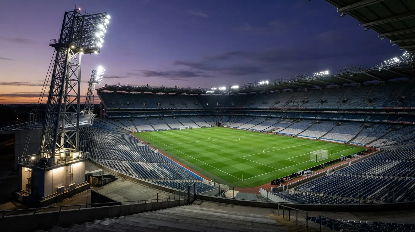 An empty football stadium with floodlight masts at dusk