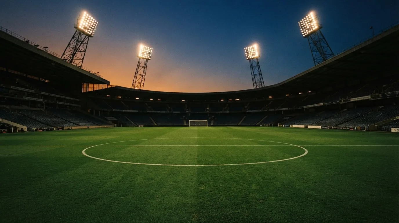 An empty football stadium with floodlight masts at dusk