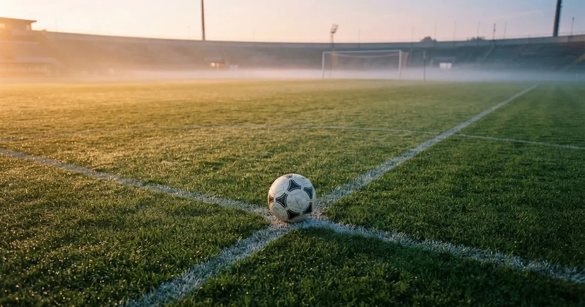 A ball on the centre spot of a grass pitch in morning light