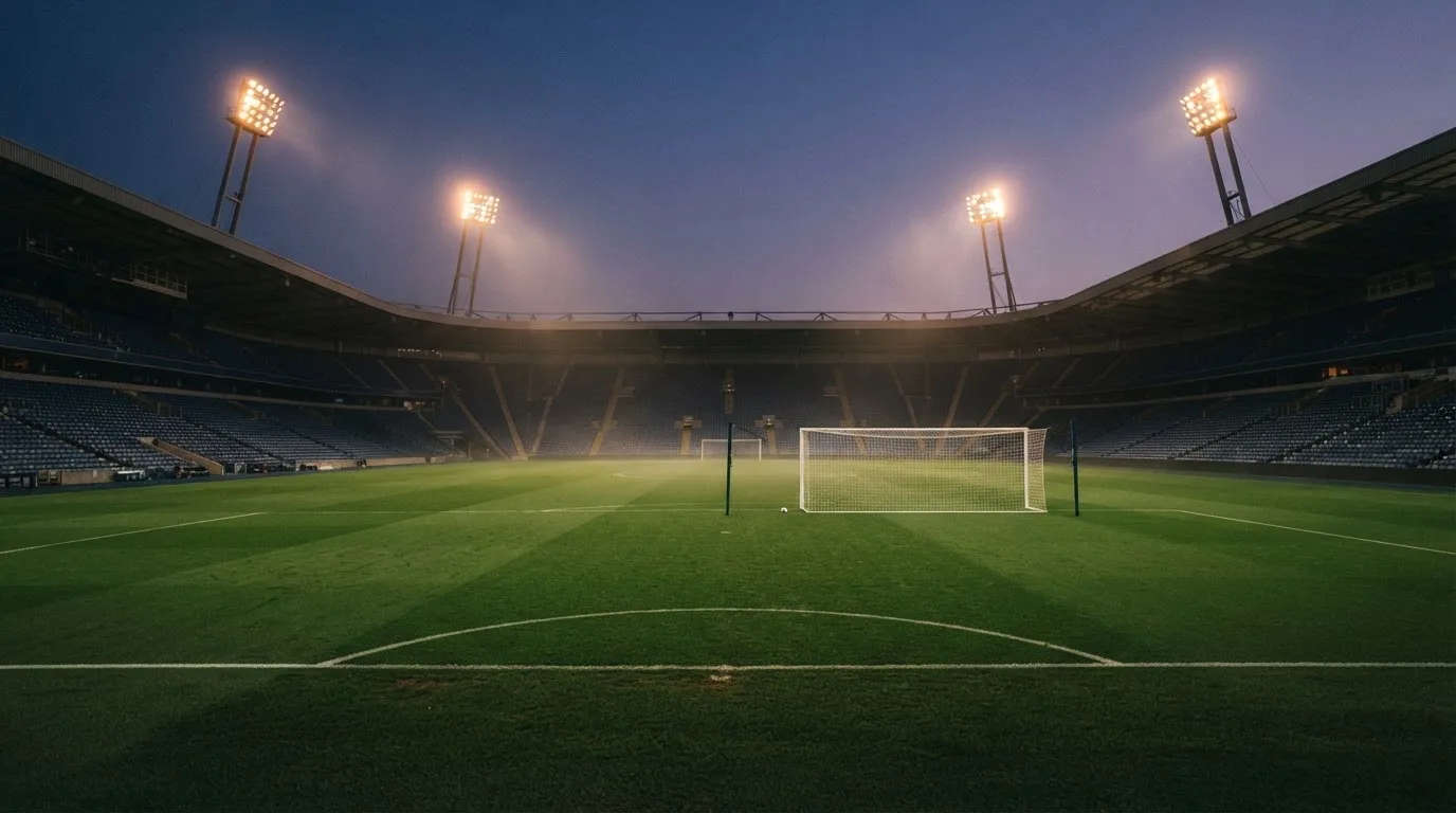 An empty football stadium with floodlight masts at dusk