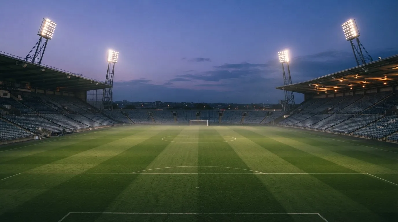 An empty football stadium with floodlight masts at dusk