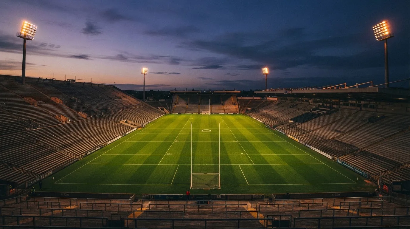 An empty football stadium with floodlight masts at dusk