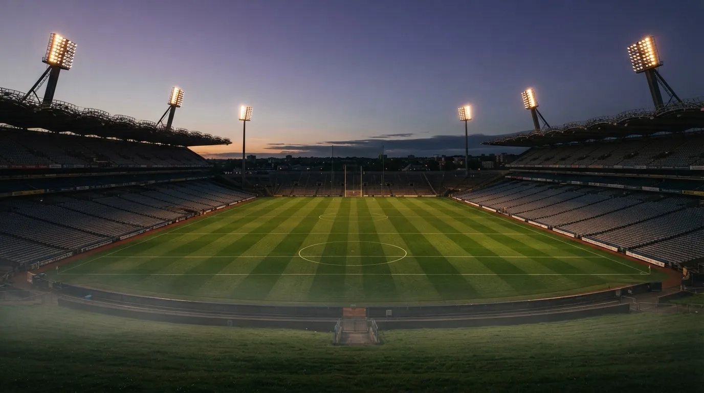 An empty football stadium with floodlight masts at dusk
