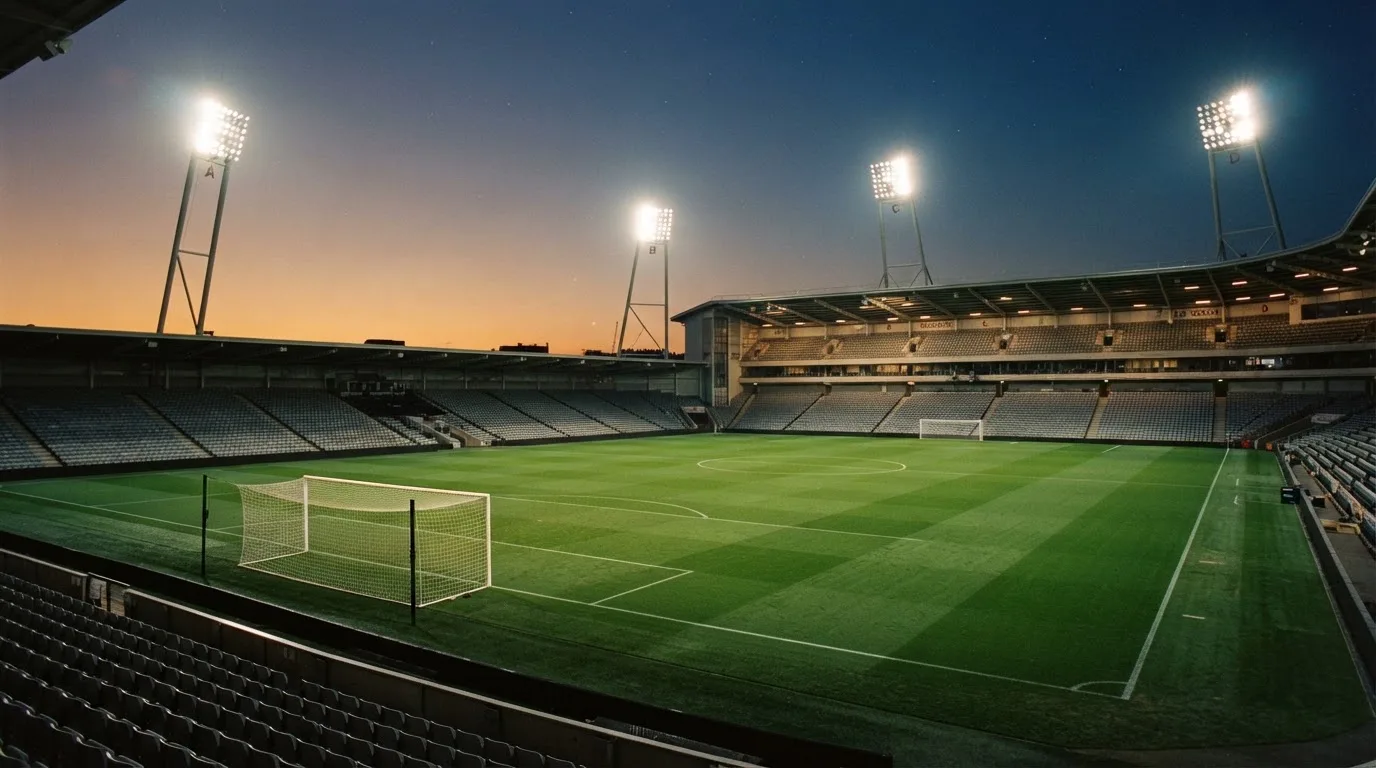 An empty football stadium with floodlight masts at dusk