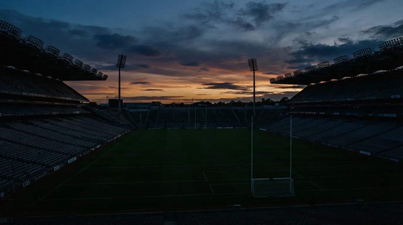 An empty football stadium with floodlight masts at dusk