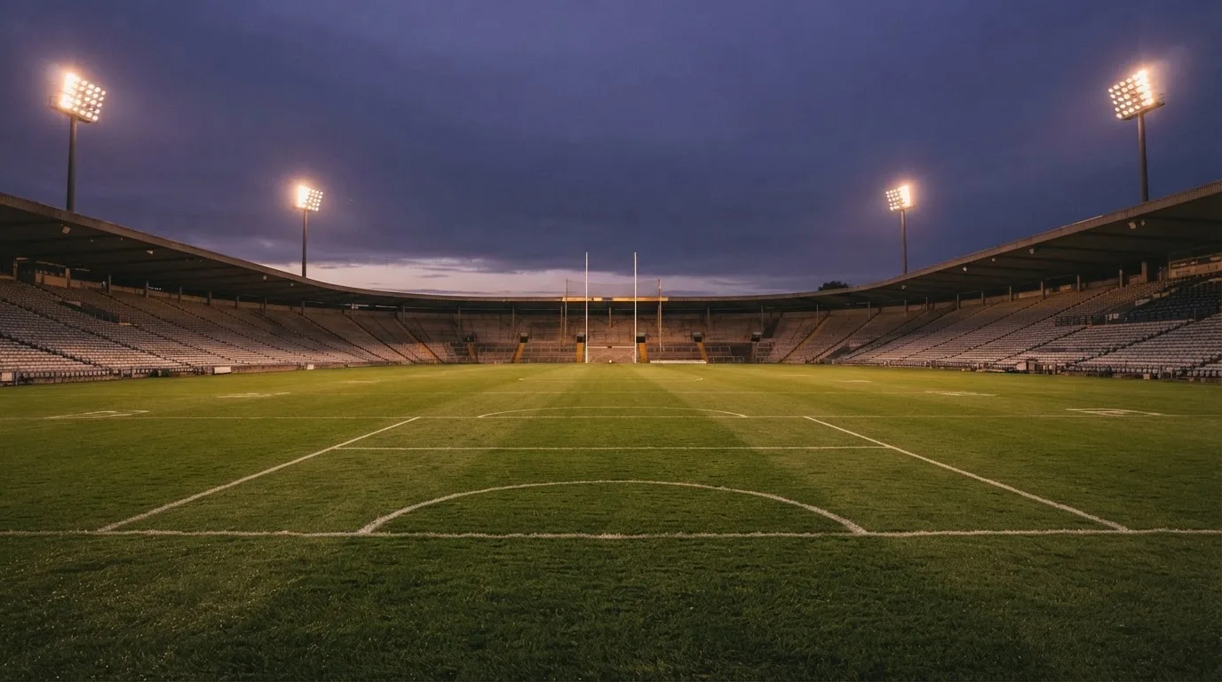 An empty football stadium with floodlight masts at dusk