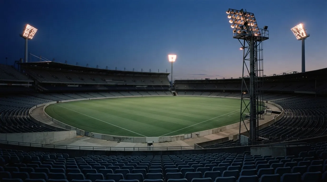 An empty football stadium with floodlight masts at dusk