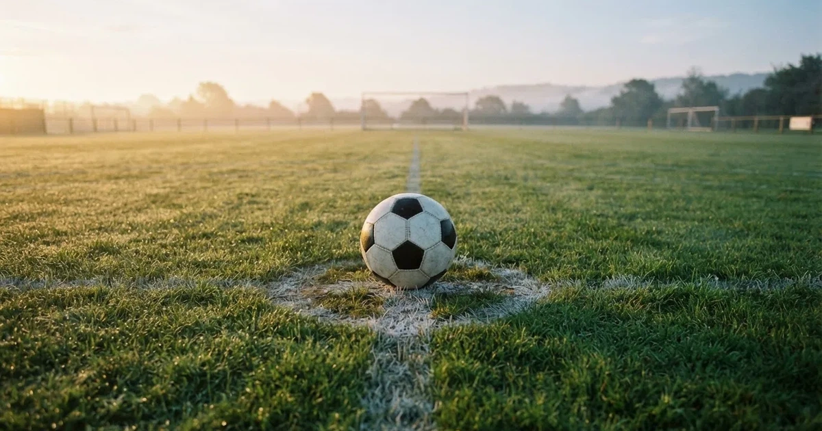 A ball on the centre spot of a grass pitch in morning light