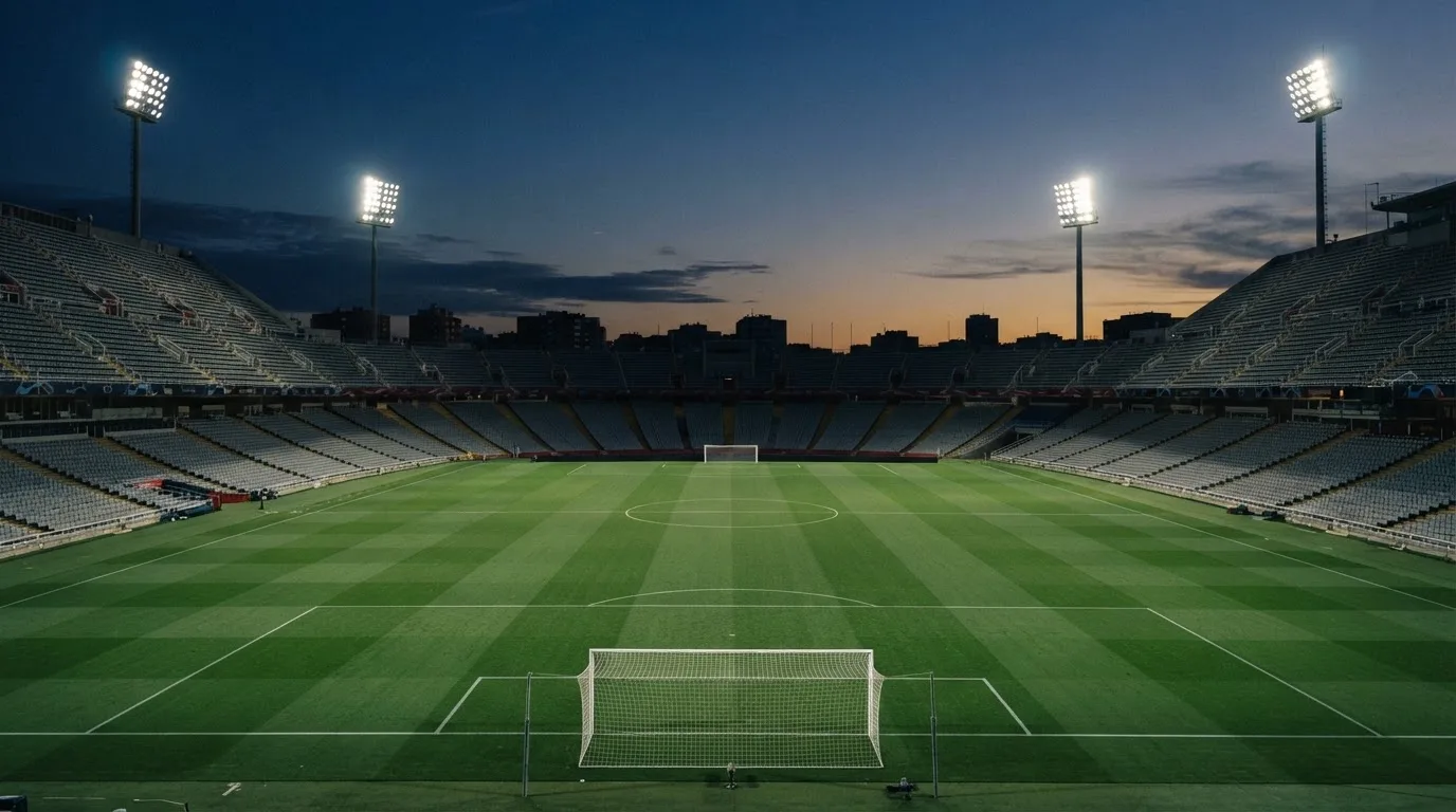 An empty football stadium with floodlight masts at dusk