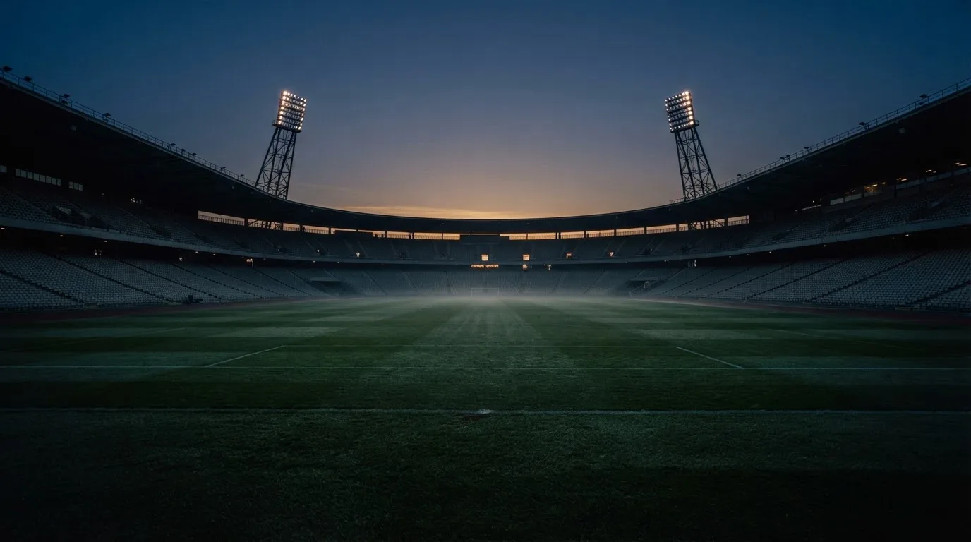An empty football stadium with floodlight masts at dusk