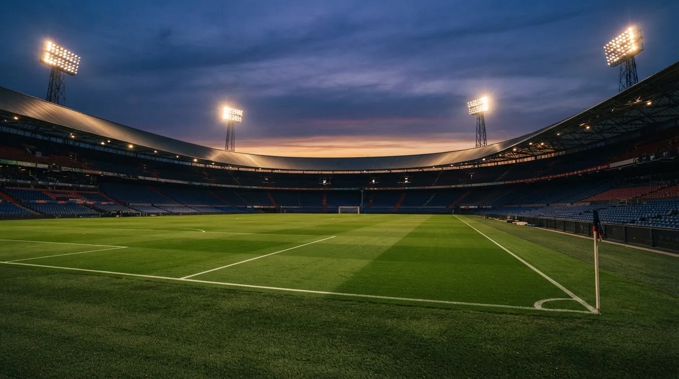 An empty football stadium with floodlight masts at dusk