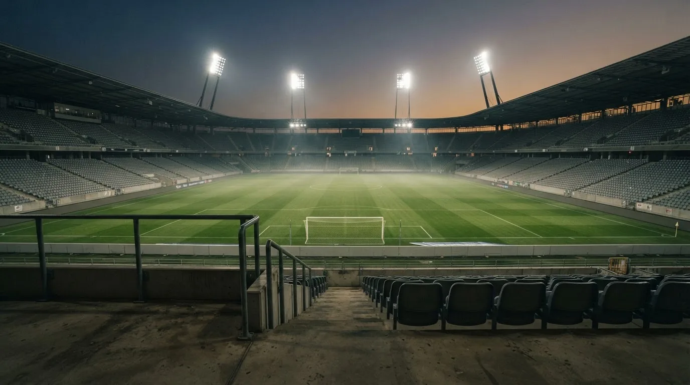 An empty football stadium with floodlight masts at dusk