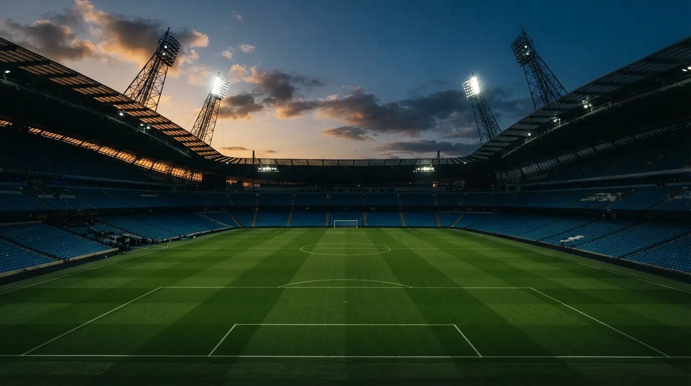 An empty football stadium with floodlight masts at dusk