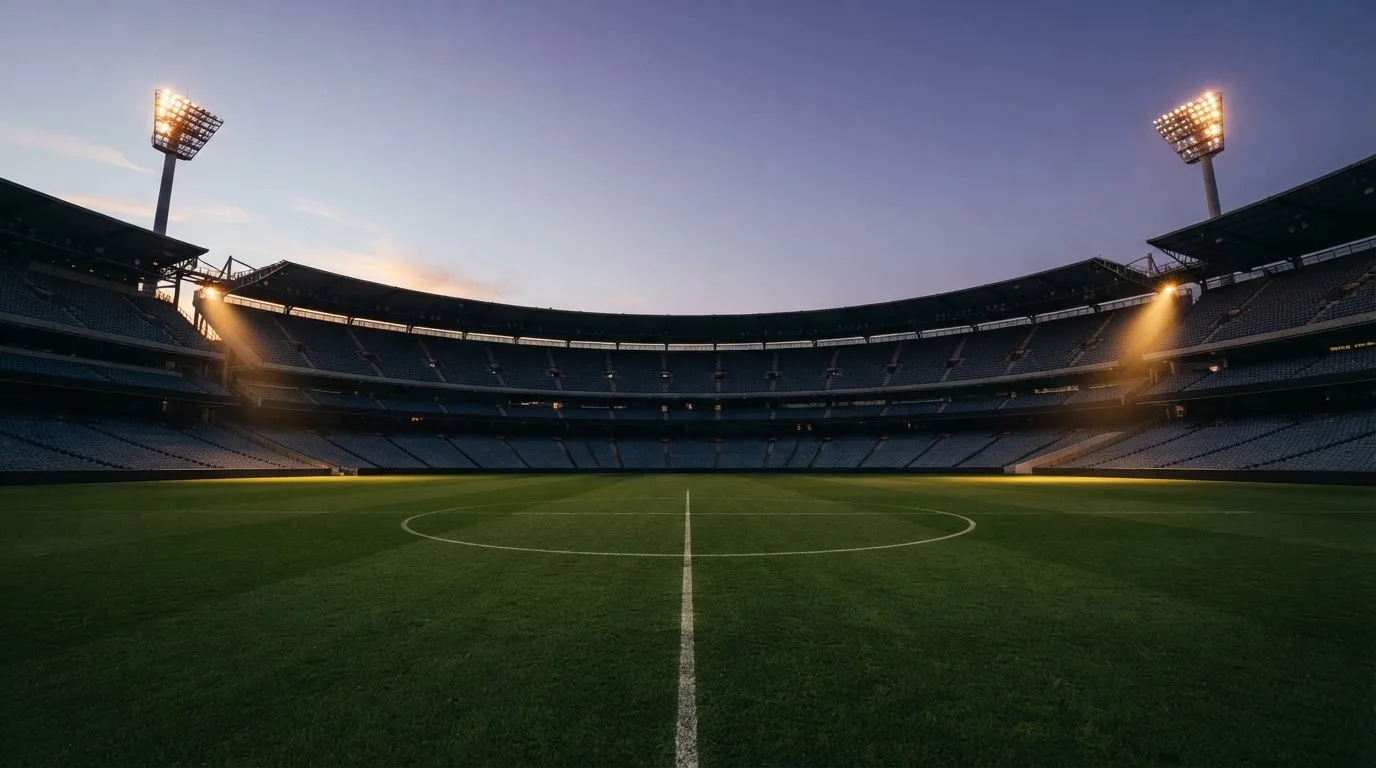 An empty football stadium with floodlight masts at dusk