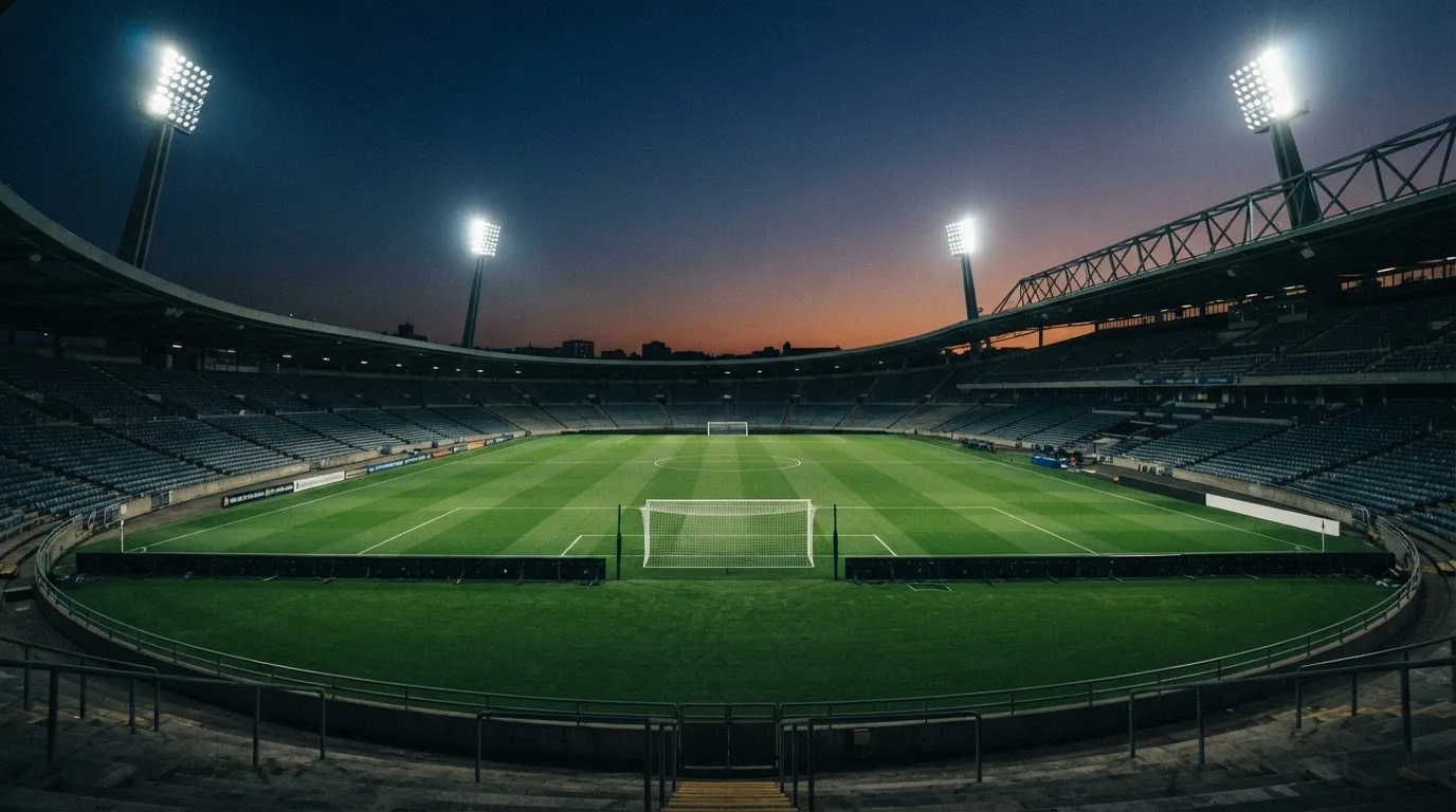 An empty football stadium with floodlight masts at dusk