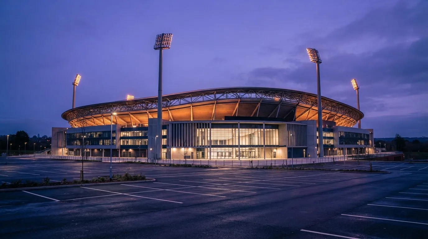 An empty football stadium with floodlight masts at dusk
