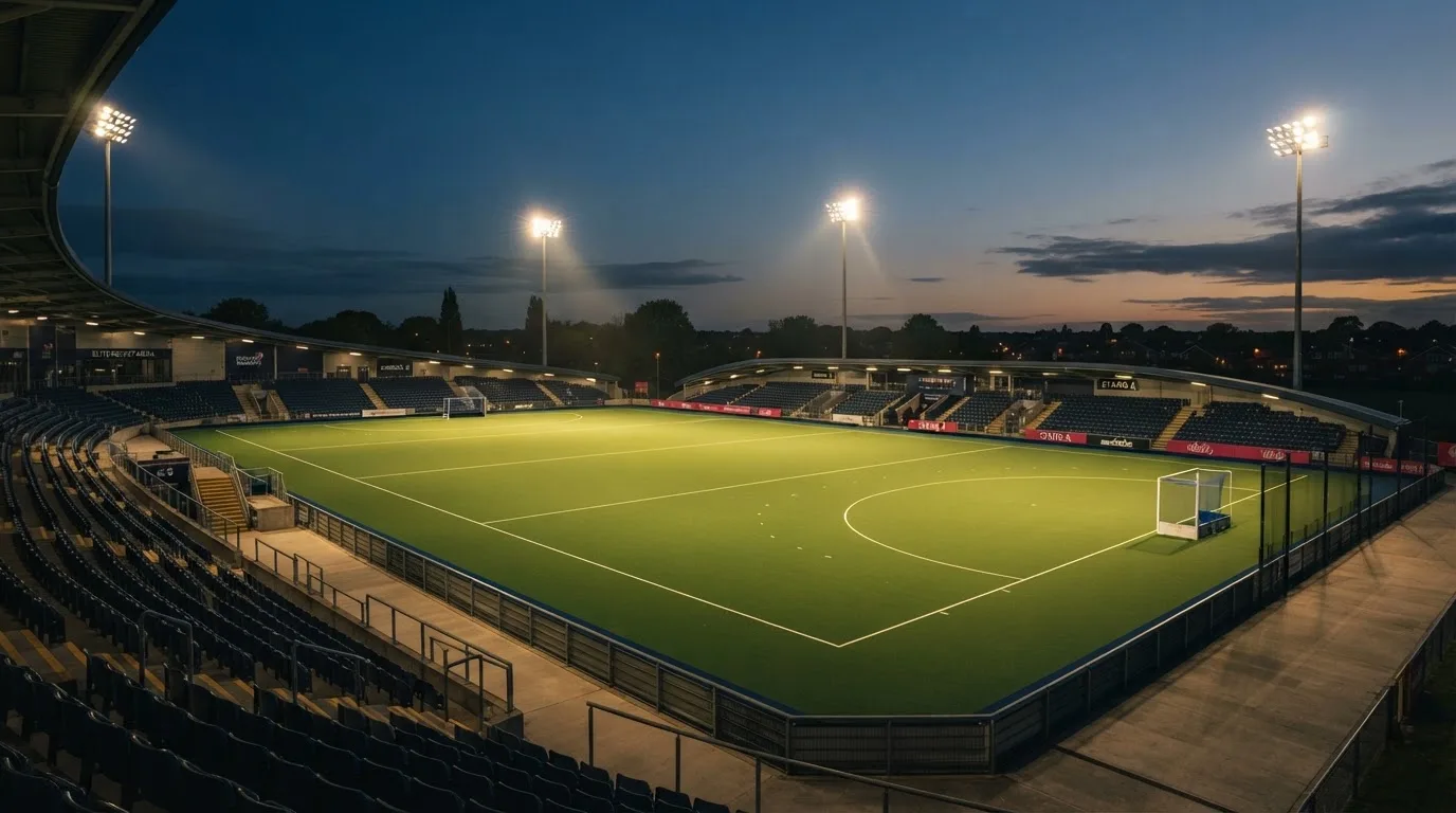 An empty football stadium with floodlight masts at dusk